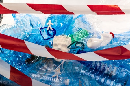 Fenced with line. Unreal models of population being closed with unprocessed plastic garbage and...