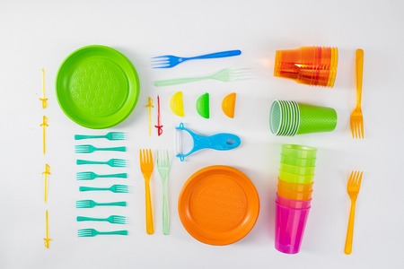 Mindful using. Bright plates and forks lying with skewers and cups made of cheap dangerous plastic