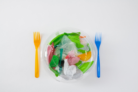 Prepared fork nearby. Transparent package with trash and plastic bags inside as literal meal for our environmentの写真素材
