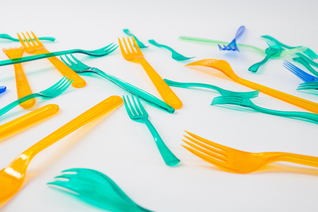 Affecting nature. Green and orange transparent forks being placed on white surface as mindful...
