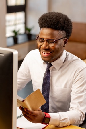 Successful project. Positive African American man being in a good mood while finishing a successful...