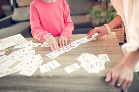 Wearing smart watches. Close up of granny and girl wearing smart watches studying letters together at the weekendの写真素材