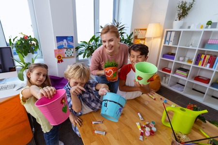 Happy pupils. Pupils feeling happy showing their cool buckets for plants after coloring them