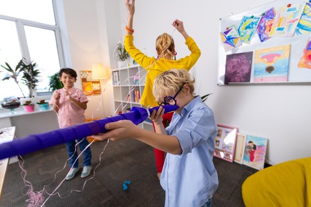Playing tricks. Teacher and two handsome smart schoolboys playing tricks after nice art lesson