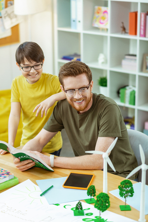 Discovering plastic model. Smiling interested man in clear glasses carrying opened book and paying attention of his student to modelの写真素材