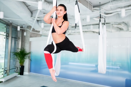 Young woman. Young dark-haired woman wearing black top and leggings doing antigravity yoga