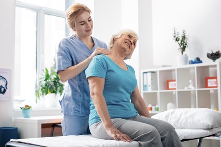 Staying healthy. Pleasant grey haired woman receiving neck massage while visiting the hospitalの写真素材