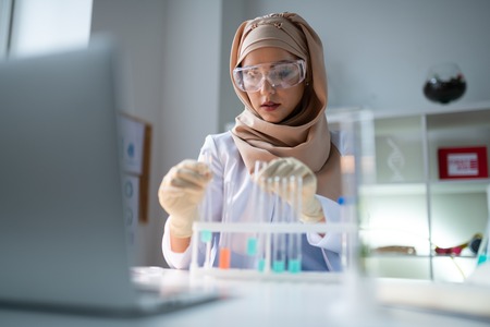 Test tubes. Young chemist wearing gloves working with test tubes full of chemical agents