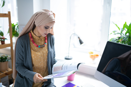 Teacher reading. Beautiful Muslim teacher wearing nice stylish necklace reading the bookの写真素材