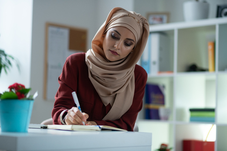 Making notes. Young appealing woman with natural makeup making some notes while workingの写真素材
