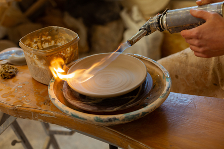 Experience in pottery. Pottery master baking clay plate with special apparat while finishing process of creatingの写真素材