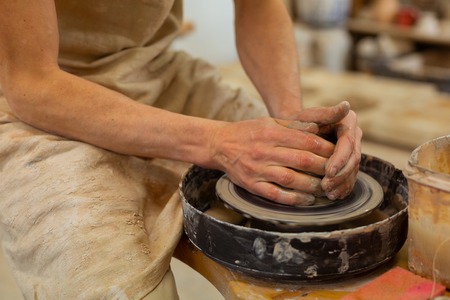 Master gently processing. Experienced man in dirty apron having strong bare hands and forming new...