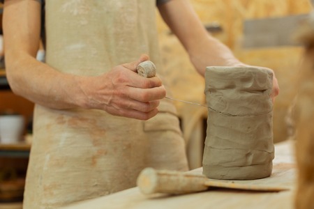 Measuring needed amount. Accurate master cutting necessary piece of clay with wire tool for future usesの写真素材