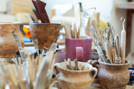 Covered in clay. Pottery tools for carving and creating new figures being collected in old clay potsの写真素材