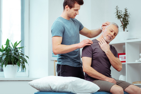 Preparing for neck massage. Nice aged man leaning his head while preparing for neck massageの写真素材