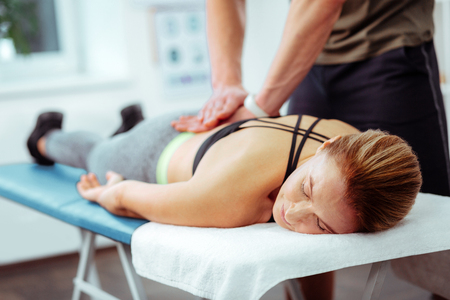 So relaxing. Nice middle aged woman lying on the medical bed while enjoying her back massageの写真素材