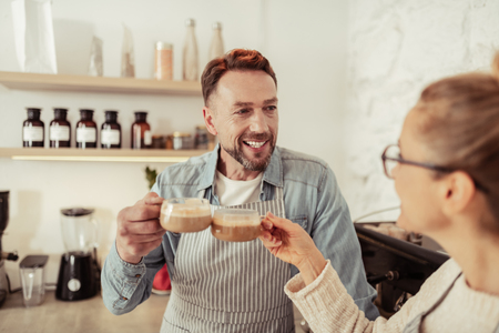 Common pastime. Happily smiling married couple drinking coffee together in the kitchen.の写真素材