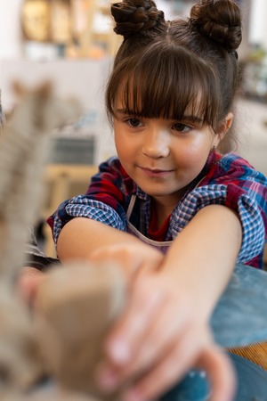 Preschool girl. Cute dark-eyed preschool girl with nice hairstyle feeling involved n sculpting clayの写真素材