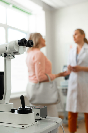Oculist cabinet. Communicative patient having important discussion with doctor while visiting equipped cabinetの写真素材