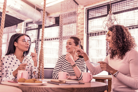 Emotional student. Curly student feeling emotional after guessing the word playing the game with her friends in cozy cafeteriaの写真素材
