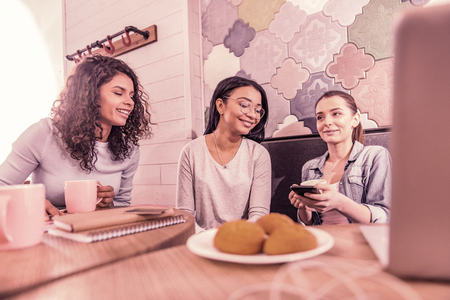 Young mothers. Three good-looking young mother having rest while meeting in cafeteria eating biscuits and drinking teaの写真素材
