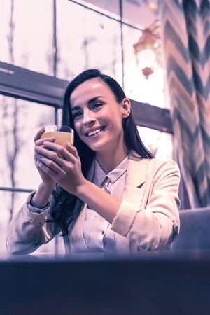 Orange juice. Nice positive woman smiling while taking a glass of juiceの写真素材