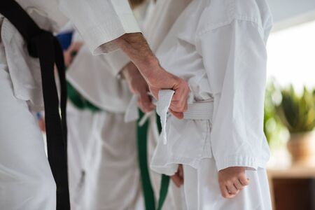 Helpful trainer. Helpful aikido trainer with black belt tying belt for his student