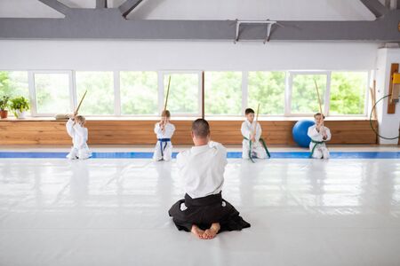 Talented children. Four talented boys and girls sitting near window learning aikido movements