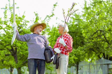 Pensioners laughing. Couple of beaming pensioners laughing before planting trees near their cottageの写真素材