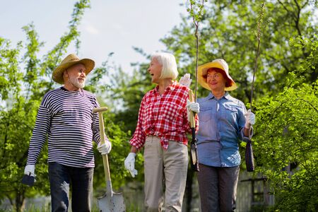 Laughing while walking. Retired active man and women laughing while walking to plant trees togetherの写真素材