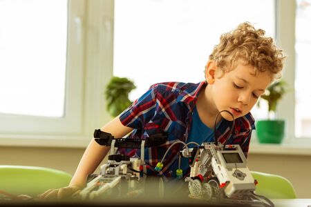 Interesting occupation. Nice young boy looking at the vehicle model while being interested in roboticsの写真素材