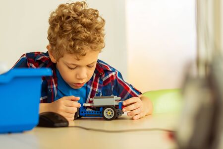 Developing ideas. Smart young boy developing bright ideas while thinking about the car model