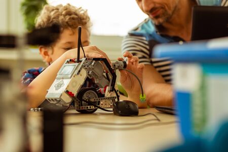 Artificial intelligence. Selective focus of a small robot being constructed by a small cute child