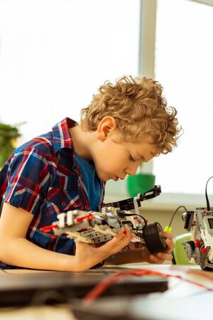 Smart child. Nice smart boy holding a vehicle model while enjoying technical engineering