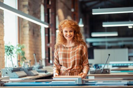 Woman smiling. Cheerful red-haired woman wearing nice dress working in publishing office smilingの写真素材