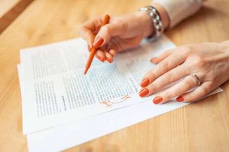 Red nails. Close up of woman with red nails making some notes in paper while working
