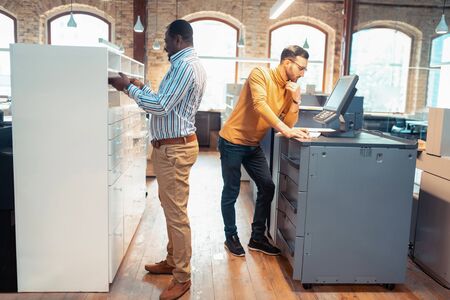 Two men cooperating. Two mature professional men cooperating while working on design of the bookの写真素材