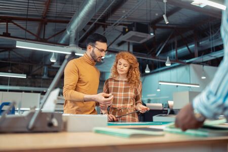 Man cooperating. Bearded dark-haired man cooperating with beautiful red-haired graphic designer
