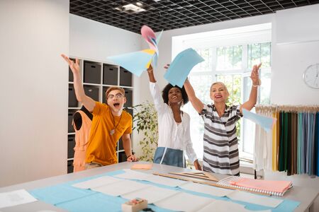 Success at work. Three cheerful creative people standing in a studio while celebrating the creation...