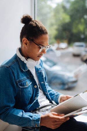 Interesting article. Kind brunette man sitting on windowsill and preparing for test paperの写真素材