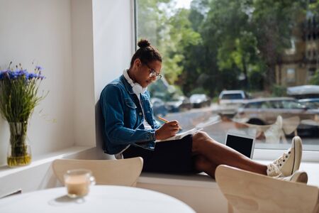 Making notes. Attentive international male person sitting in semi position and making notesの写真素材