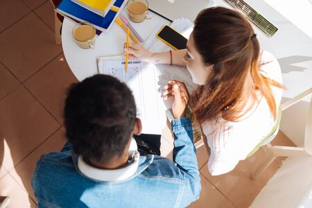 Collective work. Attentive brunette male listening to his friend while completing taskの写真素材