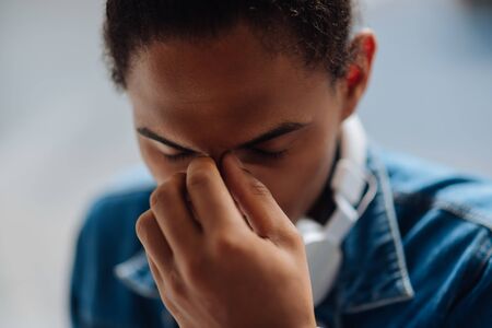 Have a problem. Concentrated brunette male keeping eyes closed while having breakの写真素材