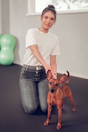 Woman with dog. Beautiful young woman wearing white t-shirt sitting on floor near her cute brown dogの写真素材