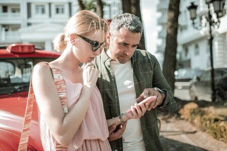 Thinking together. Concentrated man helping his wife understanding how to use her new smartphone.