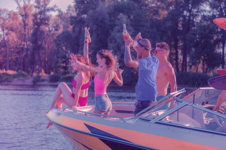 Travel companions. Side view of two smiling young couples riding a holiday cruiser and having a good timeの写真素材