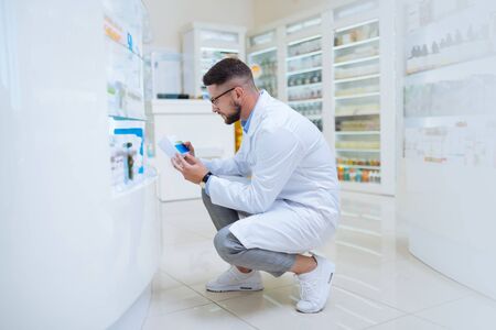 White snickers. Serious young consultant wearing white sneakers while being in the pharmacyの写真素材