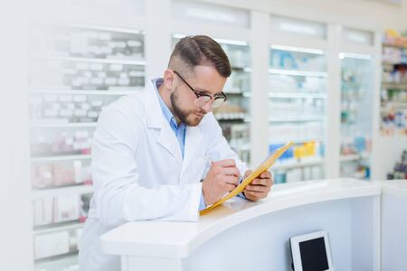 Analyzing results. Handsome brunette man bowing head while checking list of medicineの写真素材