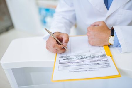 Fill in information. Stylish pharmacist wearing watches, leaning fist on tableの写真素材