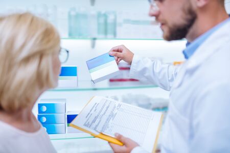 Pills presentation. Attentive blonde woman looking at shelf and being in all earsの写真素材